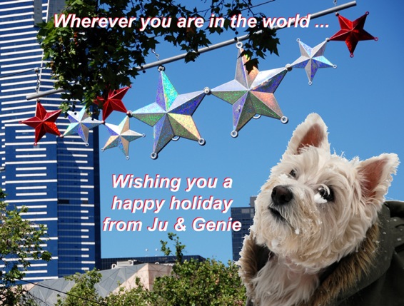 Colour photograph of a Westie in the snow set in front of xmas decorations in the street in the sunshine, bearing the text Wherever you are in the world...Wishing you a happy holiday from Ju & Genie