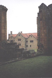 shows the manor house through a break in the wall