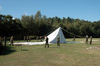 Colour photograph of a marquee being taken down by soldiers - third in a series of four