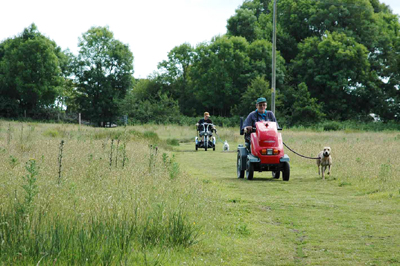 Colour photograph of Karen and her dog Rosie, me and my dog Genie, riding the offroad scooters over the field.