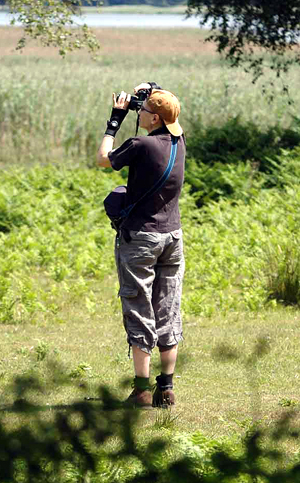 Colour photograph of me standing in front of the reed beds, taking a photograph.