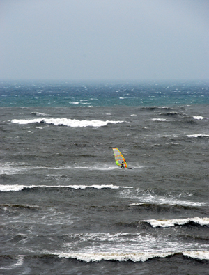 Colour photograph of a windsurfer surfingin big seas