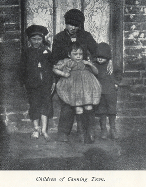 Black and white photograph from the early 20th century showing a group of children sitting on a window sill.