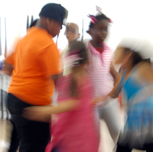 Blurred colour photograph of children dancing at speed.