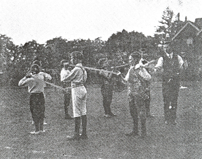 Black and white photograph of boys standing in a circle joined by their swords.