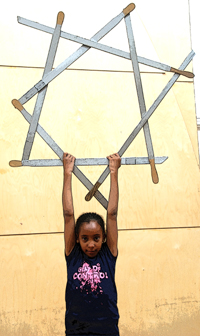 Colour photograph of a young child holding up a star made of traditional rapper swords