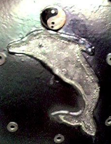 Close-up photograph of the dolpin and yin-yang symbols on the back of Ju's brace