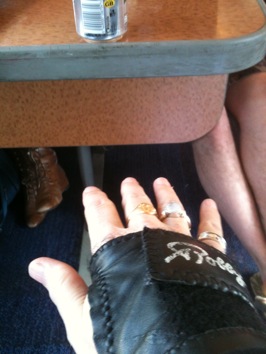 Colour photograph of a woman's hand in black leather brace, stretching towards a train table.