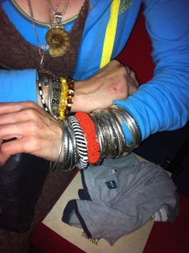 Colour photograph of a woman holding her wrists together to show off the many different bangles she is wearing.