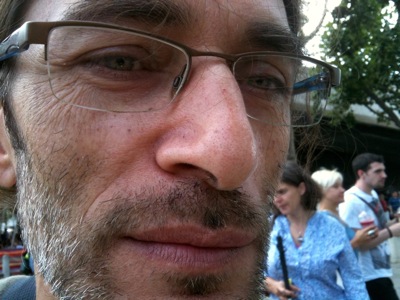 Close up colour photograph of a man with glasses and beard and a strong nose.