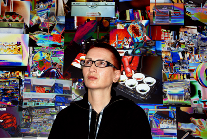 Head and shoulders portrait of Ju Gosling in front of a montage of colourful photographs (Room 147)