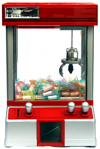 Colour photograph of a silver and red toy candy grabber machine, containing rolled up pieces of paper in coloured micro tubes