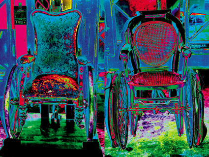 This is a colour photograph of old-fashioned wheelchairs in the Science Museum stores, digitally manipulated so that they glow with bright colours.