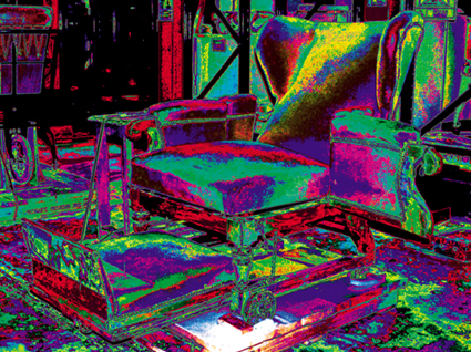 This is a colour photograph of old-fashioned wheelchairs in the Science Museum stores, digitally manipulated so that they glow with bright colours.