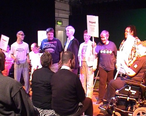 Video still of cast taking a bow, holding Regard placards